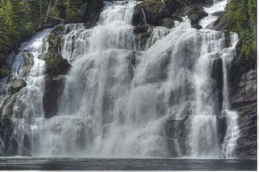A wide water fall tumbling down a tiered rock face.